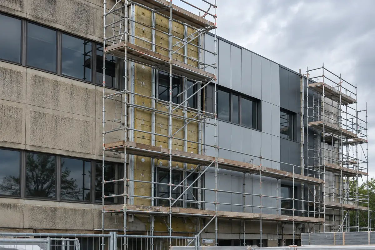 Scaffolding on a commercial building facade during recladding with new insulated panels