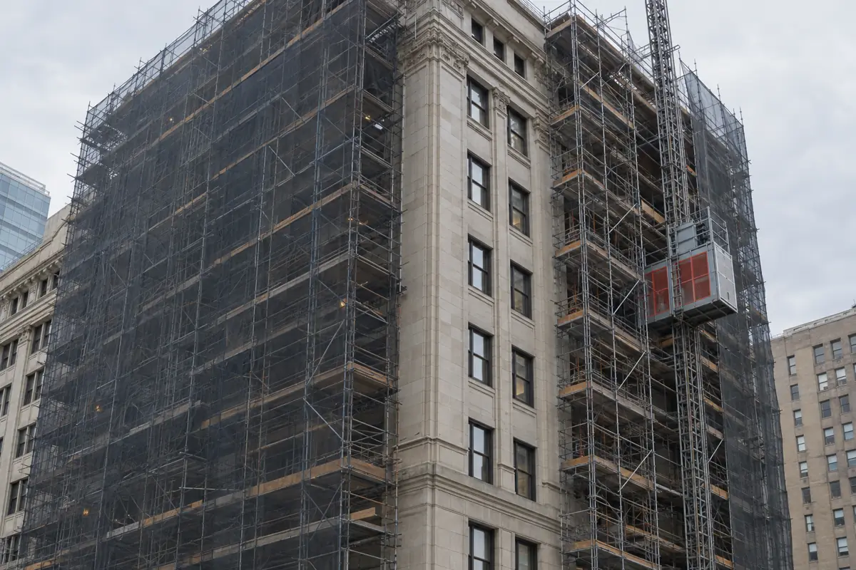 Older downtown office tower wrapped in scaffolding during conversion work